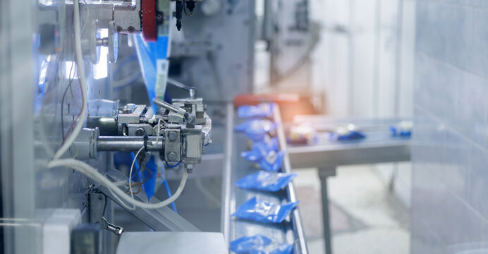 Blue bags moving along automated packing conveyor, milk food industry
