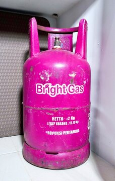 Jakarta, Indonesia - April 4th, 2026 - Bright Gas Pertamina production LPG pink tube isolated on vertical indoor background from front view.