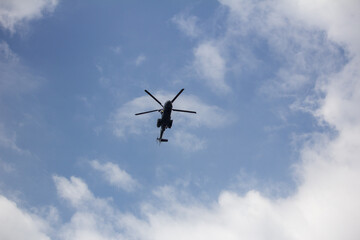 Fototapeta premium Silhouette of a helicopter flying against a cloudy blue sky