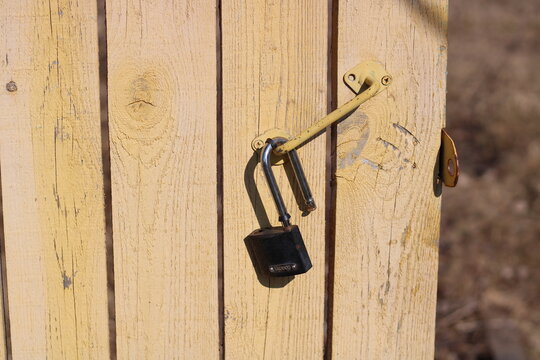 an open lock hangs on a yellow door