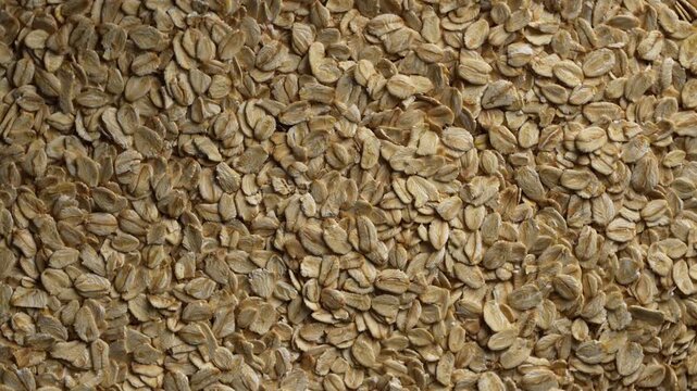 Dry oat flakes background, close up, top view, rotation. Uncooked raw oat flakes grains. Healthy breakfast and diet eating ingredients for making oatmeal porridge. Gastronomy concept, organic food