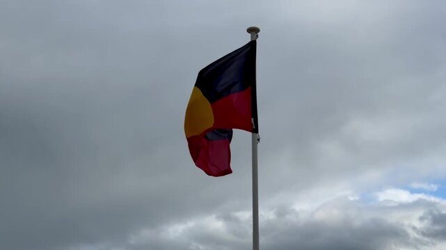 Close Up of Aboriginal Australian Flag Waving Under Cloudy Sky