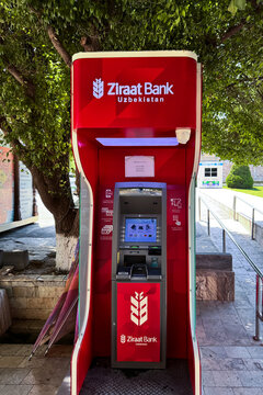 Samarkand, Uzbekistan - May 28, 2025: A bright red outdoor Ziraat Bank Uzbekistan ATM cash machine located on a paved pedestrian street