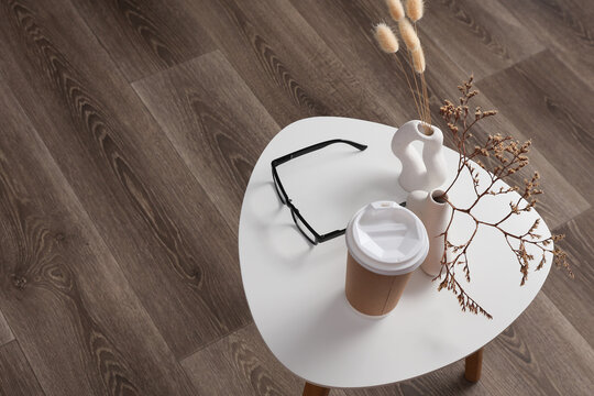 Cardboard cup, eyeglasses and Vases with dry grass on coffee table