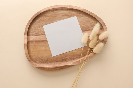 Blank card and Natural wooden tray with dry grass on beige background. Product presentation