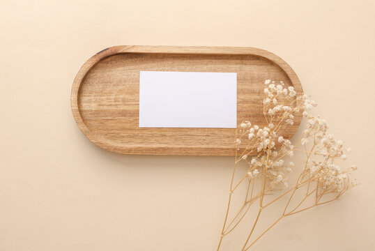 White blank business card in Natural wooden tray with dry grass on beige background
