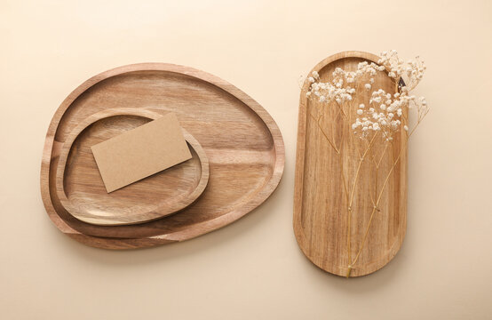 Craft business card and Natural wooden trays with dry grass on beige background. Product presentation