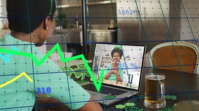 Woman at table smiling to friend speaking on screen, celebrating with graphs floating over frame