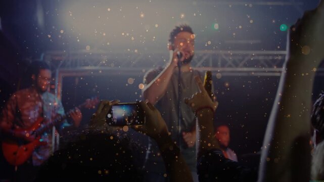 Performing band lead male singer singing into mic at club, driving crowd raising phones recording
