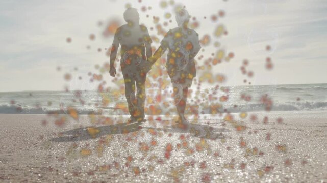 Senior couple walking toward camera on shore sun sparking warm specks hiding detail for travel ad
