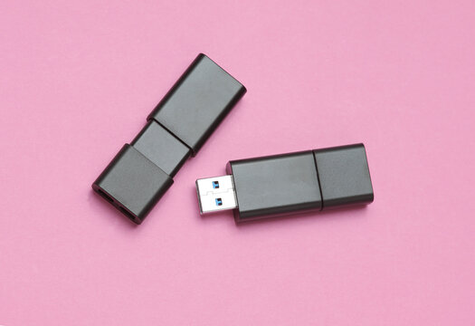 Two black USB flash drives on pink background
