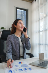 Businesswoman talking on smartphone analyzing financial data