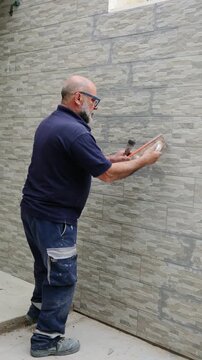 Construction worker grouting the joints between ceramic tiles on a wall at a construction site