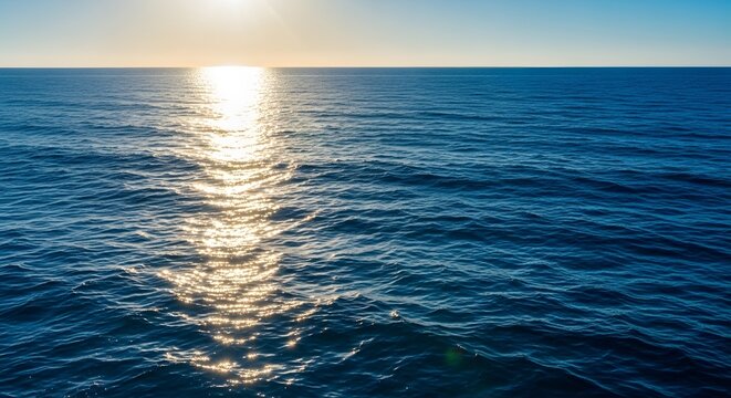 Sunset over calm ocean waves reflecting sunlight on the water surface at dawn