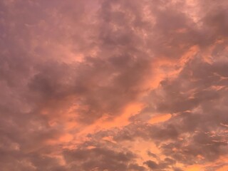 Fototapeta premium Dramatic fiery sky with glowing orange clouds at sunset, soft focus abstract texture, upward angle, rich light and shadow. Evokes intense mood, energy, and warmth. Perfect for backgrounds, nature, wea