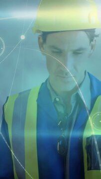 Vertical video: Site foreman in PPE using tablet checking data as camera pulling back revealing HUD