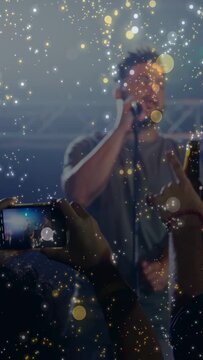 Vertical video: Music lead singer with mic singing, fans filming with phones, sparkles filling shot