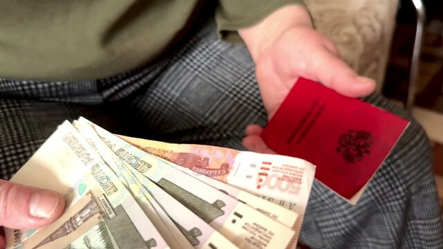 close-up of a pensioner holding a pension and a pension certificate in her hands. Video 4k