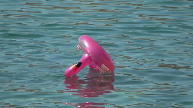 Inflatable flamingo water, pink pool float drifting on calm turquoise sea