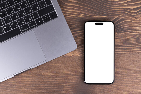 mockup mobile smartphone iPhone 15 Pro Max with blank, empty white screen template on a wood table background. Batumi, Georgia - March 19, 2026