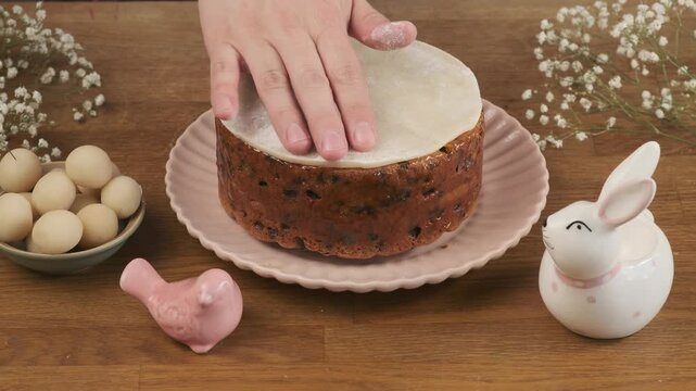 A woman decorates a British Easter cake, Simnel, with marzipan on a wooden table. Step-by-step video recipes. Horizontal video. Happy Easter.