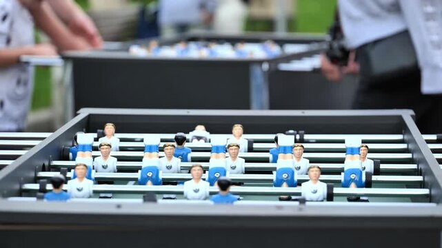 Outdoor foosball game with players on the field, enjoying recreational activity