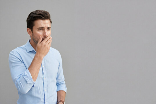 Concerned adult man covering mouth with hand while looking away sadly