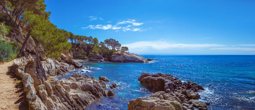 Wide-angle panoramic view of the Cam&iacute; de Ronda coastal path, which runs along the steep cliffs of the Costa Brava and the turquoise Mediterranean Sea in the background, Girona, Catalonia, Spain.