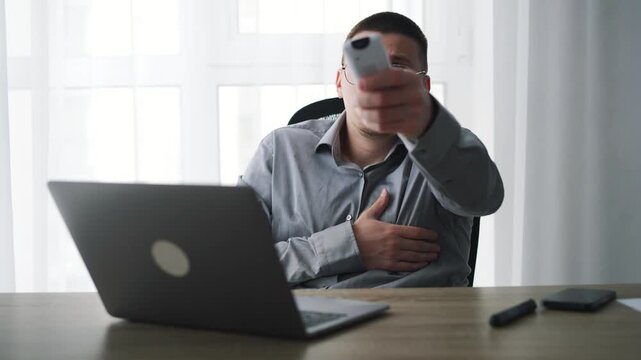 Turning on a heater in a cold office space.
A man uses a remote control to turn on an air conditioner to warm up an office.