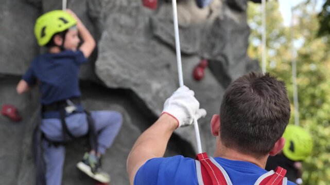 Adult belaying child during outdoor rock climbing activity for safety and adventure