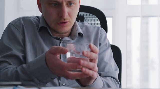 A man's hands tremble while sitting in an office with a glass of water.
Uncontrollable hand tremors, work-related stress.
Stress, tremors, hands, problems, hand tremors