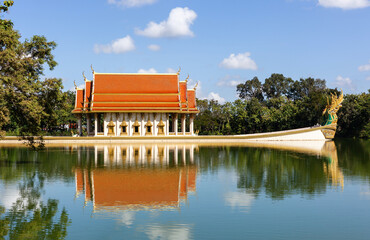 Fototapeta premium Wat Sa Prasan Suk temple reflection in lake. Traditional Thai architecture with orange roof. Located in Ubon Ratchathani, Thailand. Buddhist temple surrounded by nature.