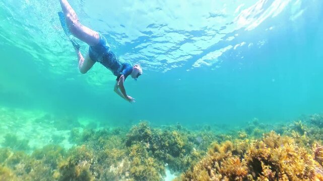 Woman snorkeling with a full-face mask over vibrant coral reef and sponge in El Nido, Palawan waters, enjoying a tranquil tropical underwater exploration and marine life viewing in Philippines islands