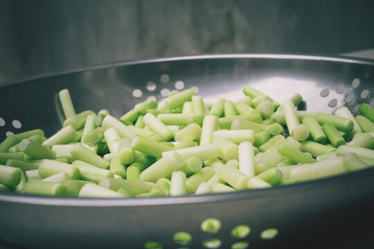 Fresh chopped green garlic scapes piled in a metal colander for healthy cooking