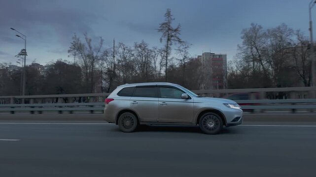 Silver SUV driving on urban highway at blue hour