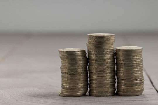 Three stacks of coins of different heights on a grey surface, side view.