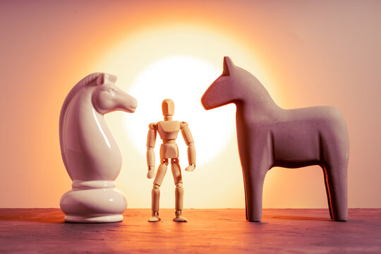 Chess knight, wooden toy horse, and wooden mannequin together on table, three figures comparison concept