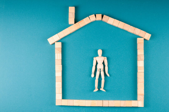 Artist doll surrounded by block-built house with chimney, home as shelter or prison theme