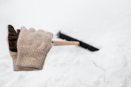 knitted gloves on the handle of a snow shovel