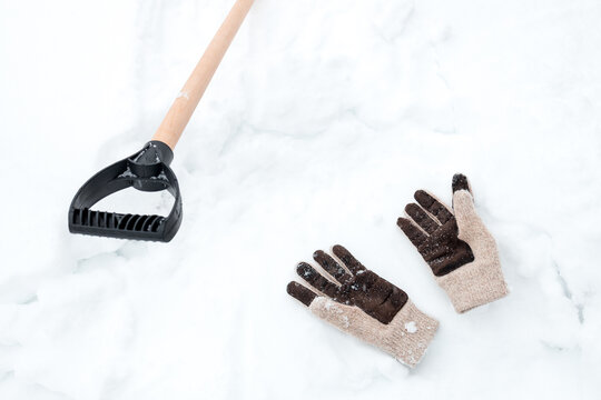 a snow shovel handle and knitted gloves in the snow
