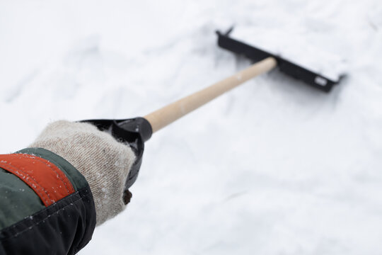 a hand gripping the handle of a snow shovel
