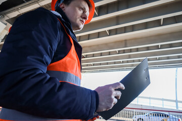 Fototapeta premium Side profile of worker looking up with clipboard in hand