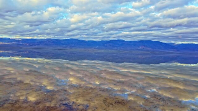 Panoramic mountain range reflecting in still mirror waters at Badwater Basin Death Valley California