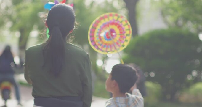 A Chinese mother and child play outdoors wearing willow leaf-woven clothes.
