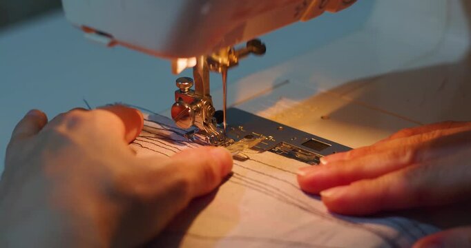 A close-up 60 fps 4k video shows hands sewing fabric on a machine, guiding it with care and precision. The rhythmic motion of the needle creates clean, even stitches.