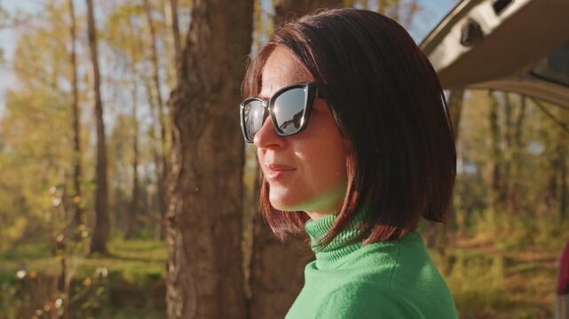 Woman finds peaceful retreat. Woman relaxes alone amidst fall trees. Serene morning scene with woman in evergreen sweater. Solitary woman enjoys calm morning in autumn forest surroundings