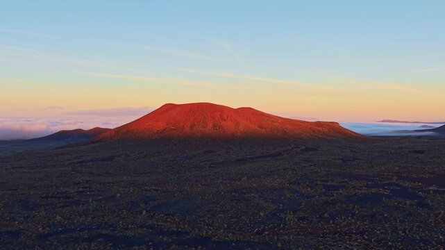 Scenic aerial perspective of volcanic cinder cones in Mojave Desert illuminated by golden sunrise light