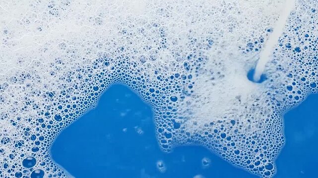 Close-up of foamy bubbles on a bright blue surface, creating a textured background effect