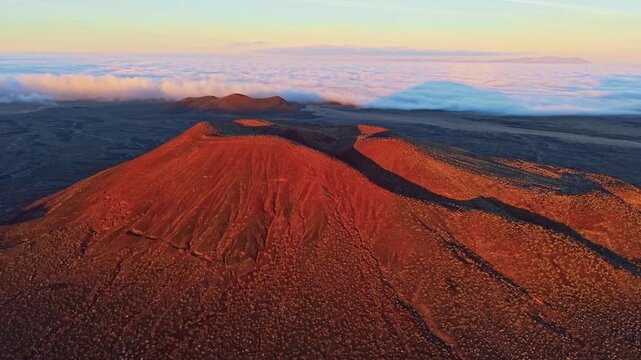 Scenic aerial perspective of volcanic cinder cones in Mojave Desert illuminated by golden sunrise light