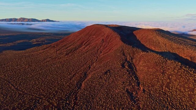 Scenic aerial perspective of volcanic cinder cones in Mojave Desert illuminated by golden sunrise light